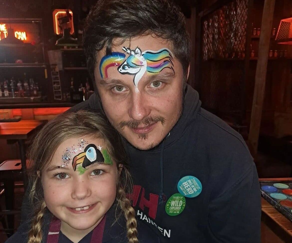 A father and daughter posing with painted faces.